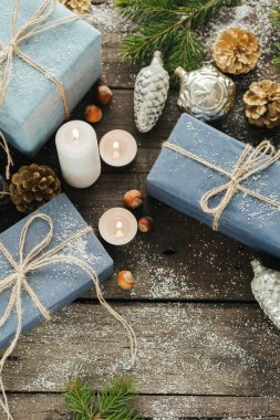 Festival hediye kutuları, mum, kar, iğne yapraklı, sepet, tarçın, çam kozalakları, deli ahşap arka plan üzerinde.