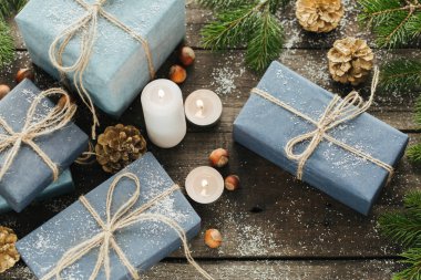 Festival hediye kutuları, mum, kar, iğne yapraklı, sepet, tarçın, çam kozalakları, deli ahşap arka plan üzerinde.