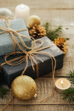 Festival hediye kutuları, mum, kar, iğne yapraklı, sepet, tarçın, çam kozalakları, deli ahşap arka plan üzerinde.