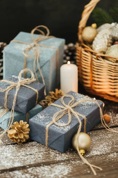 Festival hediye kutuları, mum, kar, iğne yapraklı, sepet, tarçın, çam kozalakları, deli ahşap arka plan üzerinde.