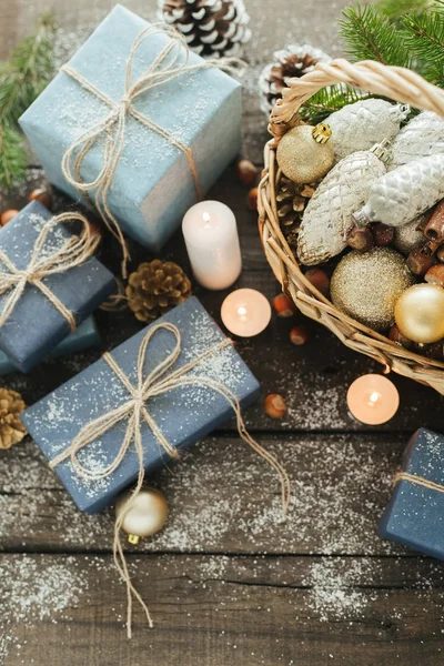 Świąteczne prezenty z pola, Świeca, śnieg, iglaste, Kosz, cynamon, sosna szyszki, nakrętki na podłoże drewniane. — Zdjęcie stockowe