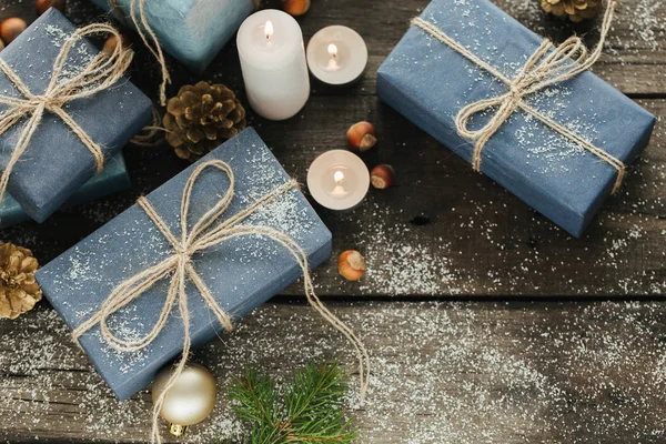 节日礼品与盒子, 蜡烛, 雪, 针叶, 篮子, 肉桂, 松果, 木制的背景坚果. — 图库照片