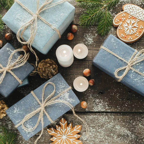 Świąteczne prezenty z pola, Świeca, śnieg, iglaste, Kosz, cynamon, sosna szyszki, nakrętki na podłoże drewniane. — Zdjęcie stockowe