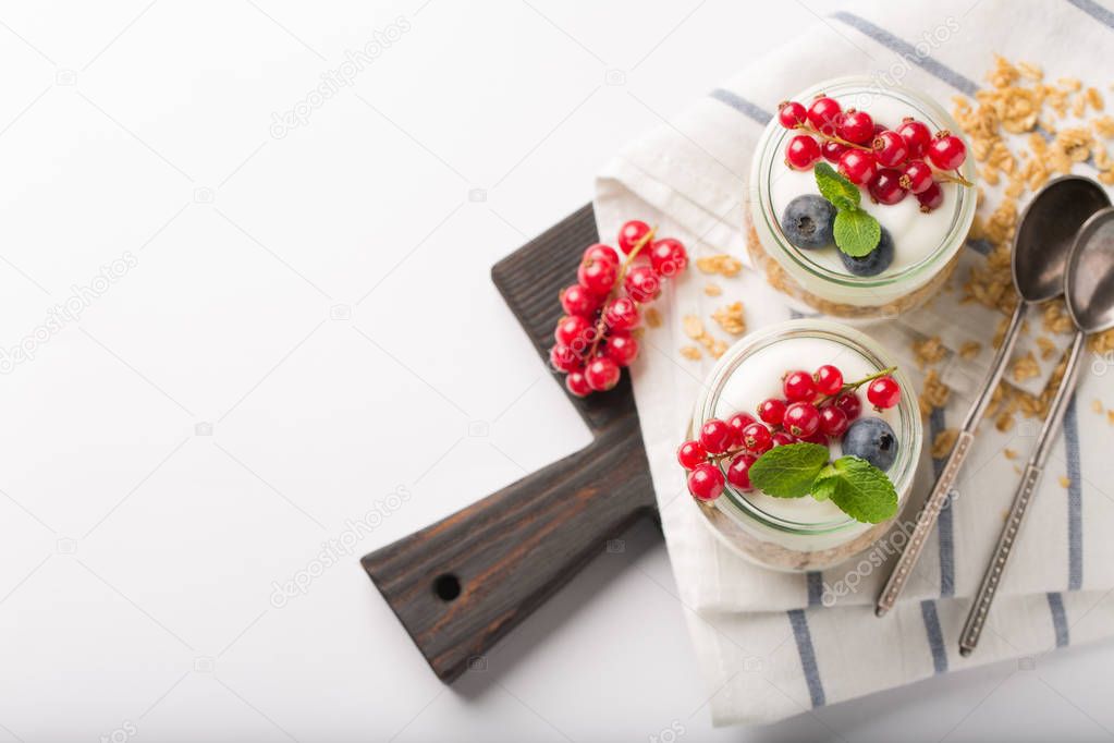 Breakfast with yogurt, granola and berries on white background. Healthy food concept. Healthy breakfast ingredient