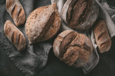 Düz-lay çeşitli ekmek seçimi. Mutfak havlu gri arka plan, üstten görünüm, kopya alanı tahıllı rustik ekmek
