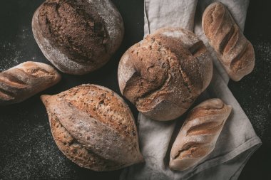 Düz-lay çeşitli ekmek seçimi. Mutfak havlu gri arka plan, üstten görünüm, kopya alanı tahıllı rustik ekmek