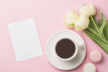 Sabah kahvesi, macarons ve kova bahar Kupası üstten görünüm çiçekler. Sabah tebrik kartı kavramı