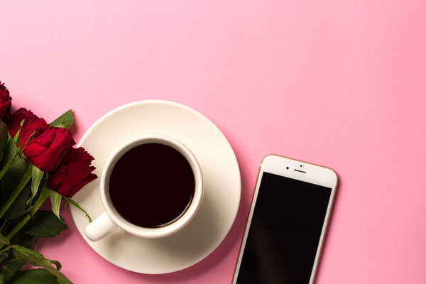 Morning concept background with roses, smartphone and a cup of coffee. Top view with space for your text