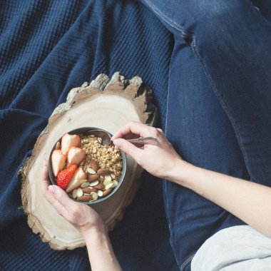 Sağlıklı kahvaltı. Granola, çilek ve kadının elinde fındık ile gri seramik kase. Diyet ve vejetaryen gıda kavramı