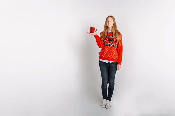 Девушка в рождественском или новогоднем свитере в Студии держит чашку ароматного кофе. Изолированное место для текста
.