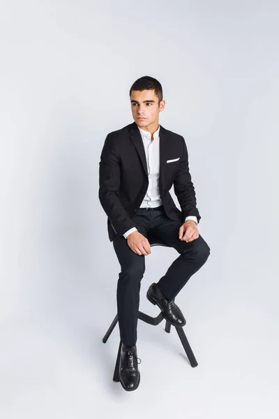 Портрет красивой позы в студии, белый фон, стильный бизнесмен, стильный мужчина, сидящий на дизайнерском стуле — стоковое фото