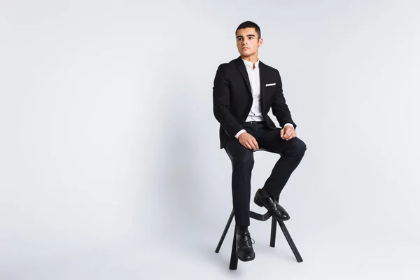 Retrato da bela posando em um estúdio, fundo branco, homem de negócios elegante, homem elegante sentado em uma cadeira de designer — Fotografia de Stock