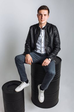 Varil üzerinde oturan adam. Stüdyo adam. Siyah ceketli çocuk. Yakışıklı adam