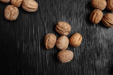 Bir sürü siyah bir ahşap zemin üzerine taze fındık. Tasarımcı için en iyi yöntemler. Fındık üzerinden güzel bir tasarım