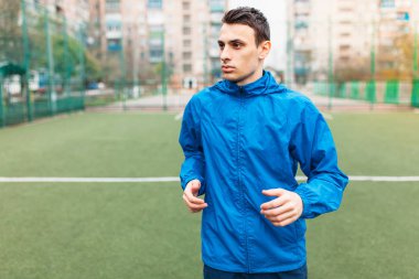 Genç bir adam spor çalış, futbol sahasında çalışır. Adam inşaat içinde açık, taze soluduğumuz hava.