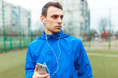 adam bir egzersiz sırasında müzik dinlemek. Genç bir adam spor çalış, futbol sahasında çalışır. Adam açık, temiz havada çalışıyor. Metin için izole yer