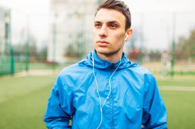 adam bir egzersiz sırasında müzik dinlemek. Genç bir adam spor çalış, futbol sahasında çalışır. Adam açık, temiz havada çalışıyor. Metin için izole yer