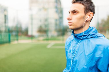 adam bir egzersiz sırasında müzik dinlemek. Genç bir adam spor çalış, futbol sahasında çalışır. Adam açık, temiz havada çalışıyor. Metin için izole yer