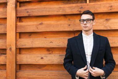 Şık, klasik kostüm, erkekte ahşap duvara yakın poz. İş tarzı, yaşam, çalışma.