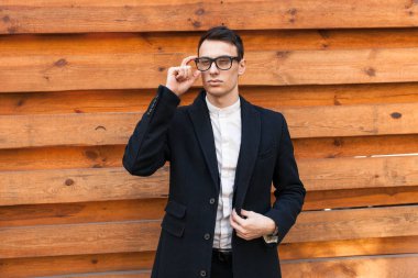 Şık, klasik kostüm, erkekte ahşap duvara yakın poz. İş tarzı, yaşam, çalışma.