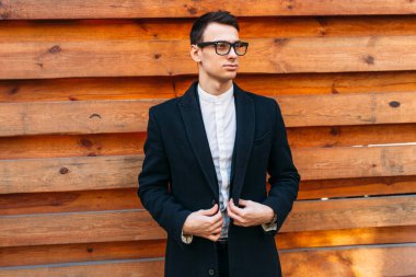 Şık, klasik kostüm, erkekte ahşap duvara yakın poz. İş tarzı, yaşam, çalışma.