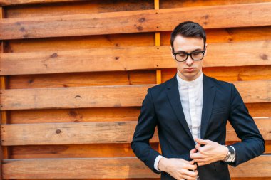 Şık, klasik kostüm, erkekte ahşap duvara yakın poz. İş tarzı, yaşam, çalışma.