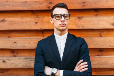 Şık, klasik kostüm, erkekte ahşap duvara yakın poz. İş tarzı, yaşam, çalışma.