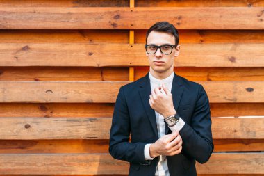 Şık, klasik kostüm, erkekte ahşap duvara yakın poz. İş tarzı, yaşam, çalışma.