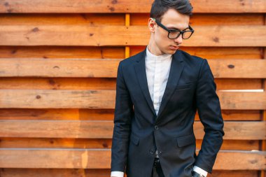 Şık, klasik kostüm, erkekte ahşap duvara yakın poz. İş tarzı, yaşam, çalışma.