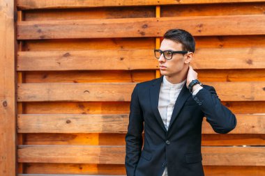 Şık, klasik kostüm, erkekte ahşap duvara yakın poz. İş tarzı, yaşam, çalışma.