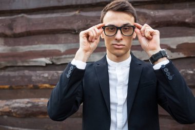 Şık, klasik kostüm, erkekte ahşap duvara yakın poz. İş tarzı, yaşam, çalışma.