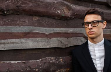 Şık, klasik kostüm, erkekte ahşap duvara yakın poz. İş tarzı, yaşam, çalışma.