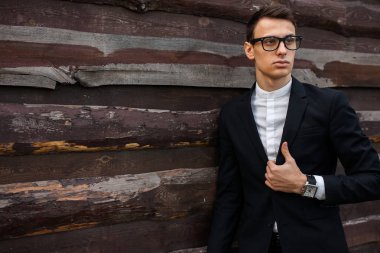 Şık, klasik kostüm, erkekte ahşap duvara yakın poz. İş tarzı, yaşam, çalışma.