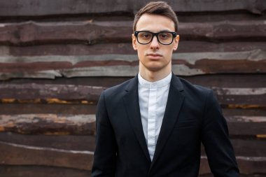 Şık, klasik kostüm, erkekte ahşap duvara yakın poz. İş tarzı, yaşam, çalışma.