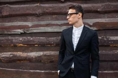 Şık, klasik kostüm, erkekte ahşap duvara yakın poz. İş tarzı, yaşam, çalışma.