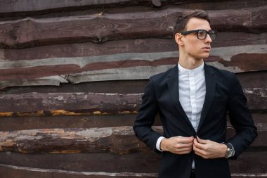 Şık, klasik kostüm, erkekte ahşap duvara yakın poz. İş tarzı, yaşam, çalışma.