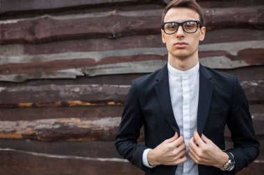 Şık, klasik kostüm, erkekte ahşap duvara yakın poz. İş tarzı, yaşam, çalışma.