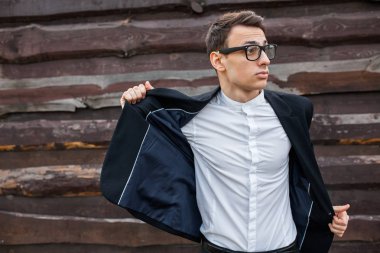 Adam onun ceketini alır. Şık, klasik kostüm, erkekte ahşap duvara yakın poz. İş tarzı, yaşam, çalışma.