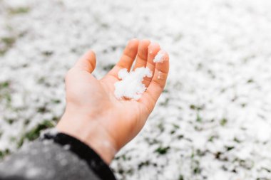 Kar adam elinde. Arka planda yeşil çimen, kar