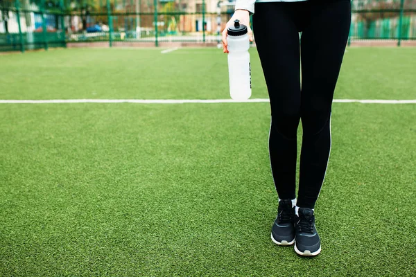 Mädchen nach dem Training, Laufen oder Sport eine Pause. im Vordergrund eine Flasche Wasser. das Mädchen arbeitet an der frischen Luft. — Stockfoto