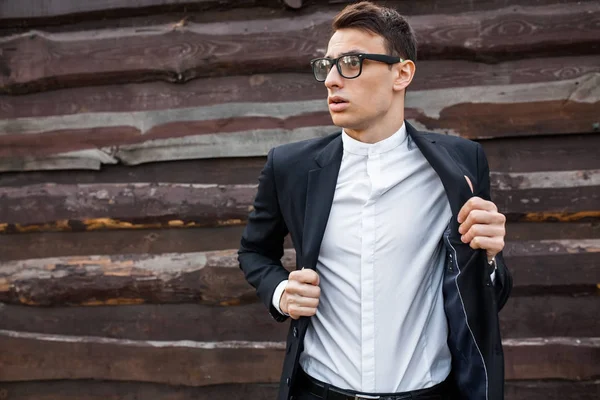 Adam onun ceketini alır. Şık, klasik kostüm, erkekte ahşap duvara yakın poz. İş tarzı, yaşam, çalışma