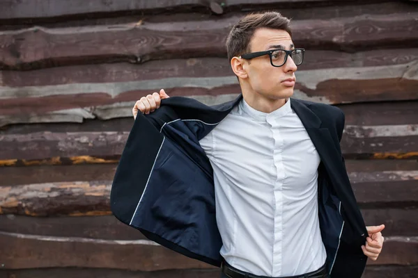 Adam onun ceketini alır. Şık, klasik kostüm, erkekte ahşap duvara yakın poz. İş tarzı, yaşam, çalışma.