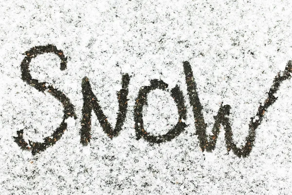 The word snow written in snow. Snowy background.