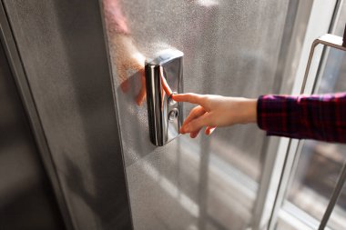 Asansörün düğmesine, düğme için izole Asansör, basma düğmesi Başlat ' için bekleyen kız ulaşan bir el başparmak presler