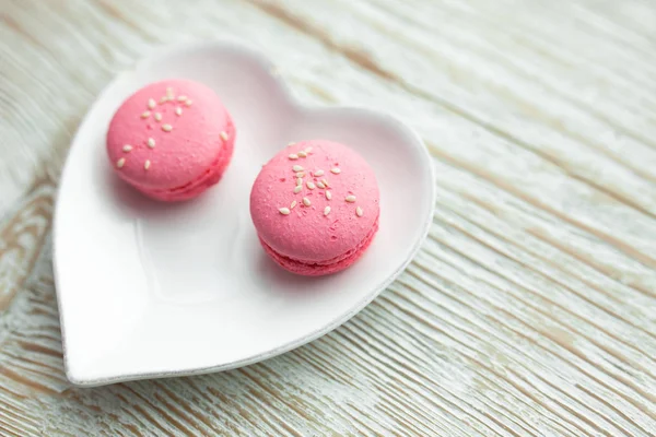 Delicious fresh macaroons on the plate is heart-shaped, lovers