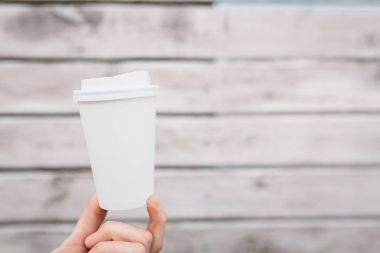 Beyaz kağıt ya da plastik bardak ortasında, yalıtılmış bir ahşap duvar arka plan üzerinde boş alan Kupası