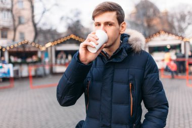 yakışıklı bir adam bir plastik bardak, içme kahve veya çay tutan bir ceketli, dışarısı soğuk
