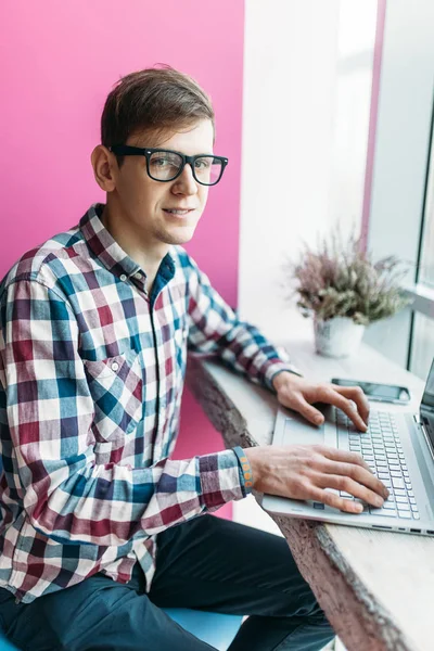 Egy fiatalember ül egy kávézó, egy laptop, a Keresés az interneten, és gépelés-ra laptop — Stock Fotó