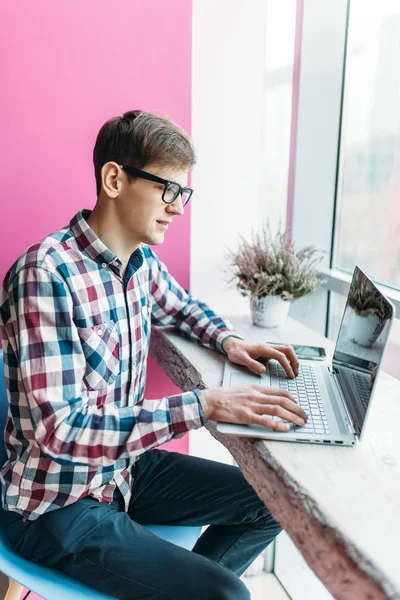 Egy fiatalember ül egy kávézó, egy laptop, a Keresés az interneten, és gépelés-ra laptop — Stock Fotó