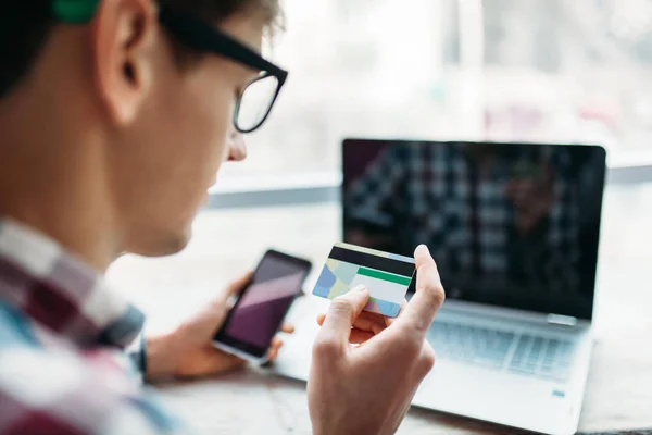 Jonge man met credit card betalingen via het Internet, het item op het Internet zoeken — Stockfoto